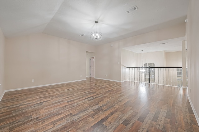 spare room featuring dark hardwood / wood-style floors, lofted ceiling, and a chandelier