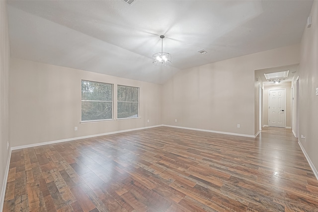 spare room with dark hardwood / wood-style flooring, a chandelier, and vaulted ceiling