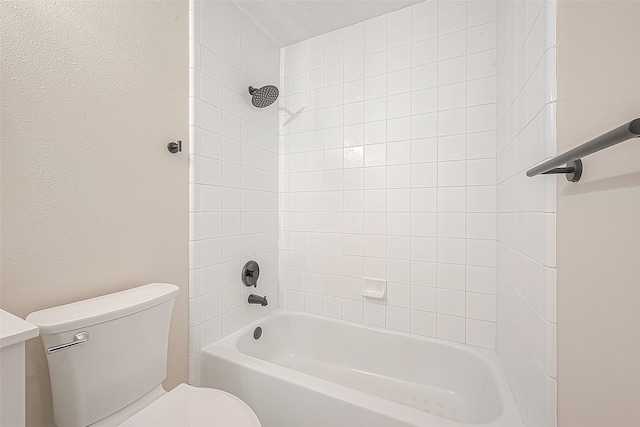 bathroom featuring tiled shower / bath combo and toilet