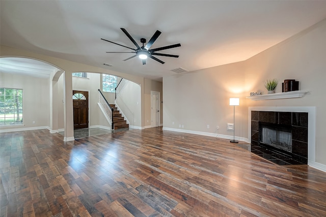 unfurnished living room featuring a fireplace, dark hardwood / wood-style floors, plenty of natural light, and ceiling fan