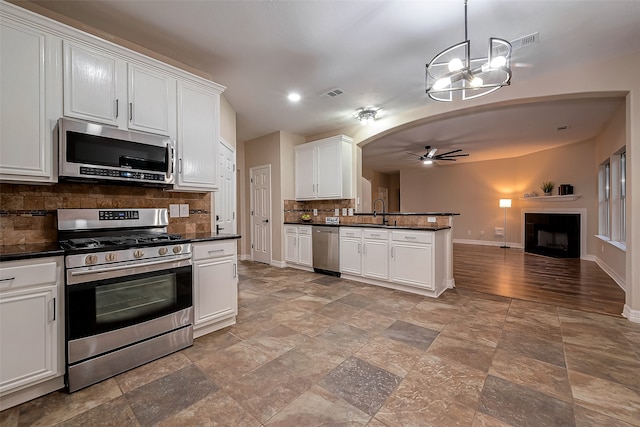 kitchen featuring tasteful backsplash, white cabinets, ceiling fan with notable chandelier, and appliances with stainless steel finishes