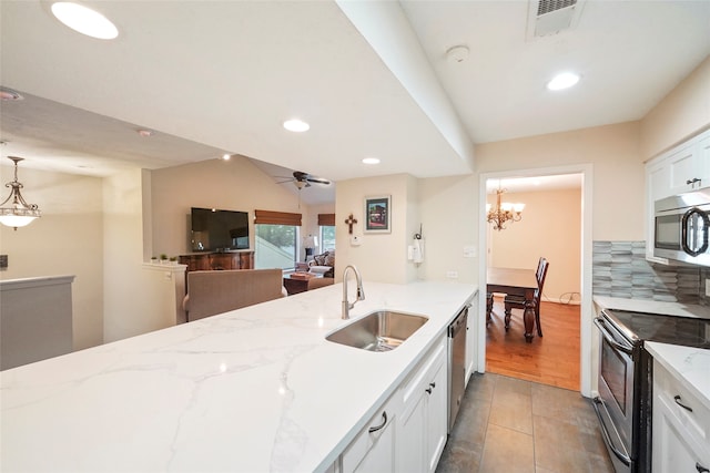 kitchen featuring ceiling fan with notable chandelier, sink, stainless steel appliances, light stone counters, and pendant lighting