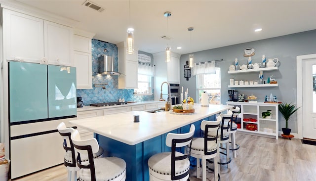 kitchen with decorative light fixtures, stainless steel appliances, white cabinetry, and a breakfast bar