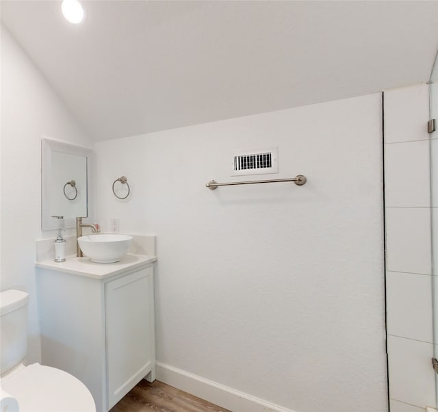 bathroom featuring lofted ceiling, toilet, vanity, and hardwood / wood-style flooring