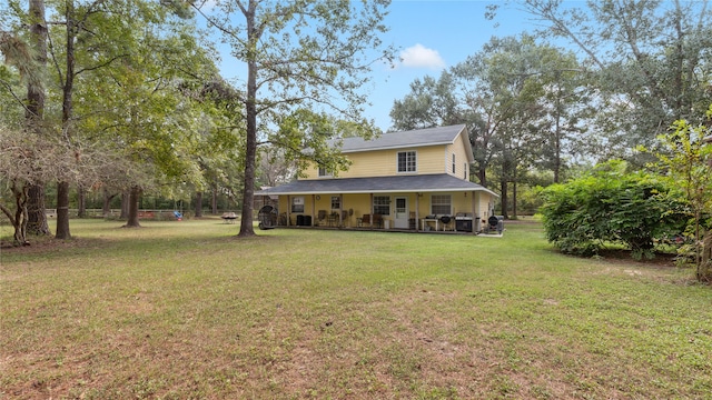 rear view of property featuring a yard and covered porch