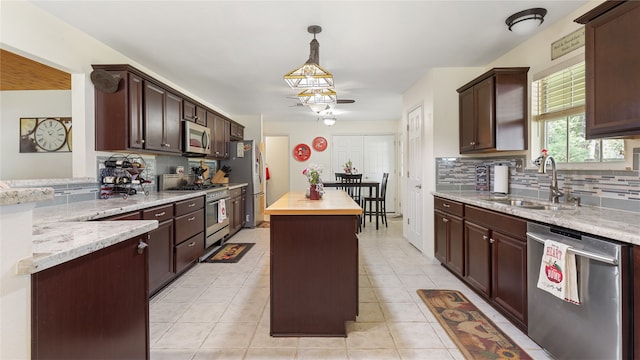 kitchen featuring appliances with stainless steel finishes, butcher block countertops, a kitchen island, pendant lighting, and sink