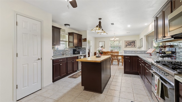 kitchen with ceiling fan with notable chandelier, a center island, a healthy amount of sunlight, and wooden counters