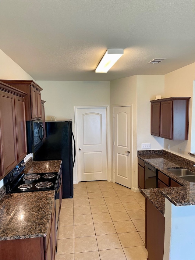 kitchen with light tile flooring, sink, range with electric cooktop, dark stone countertops, and dishwasher