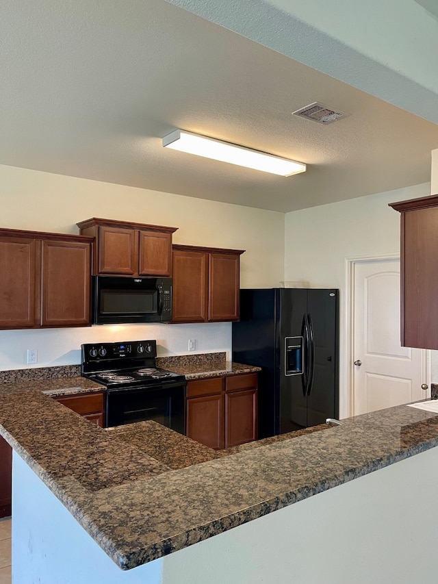 kitchen featuring a textured ceiling, kitchen peninsula, and black appliances