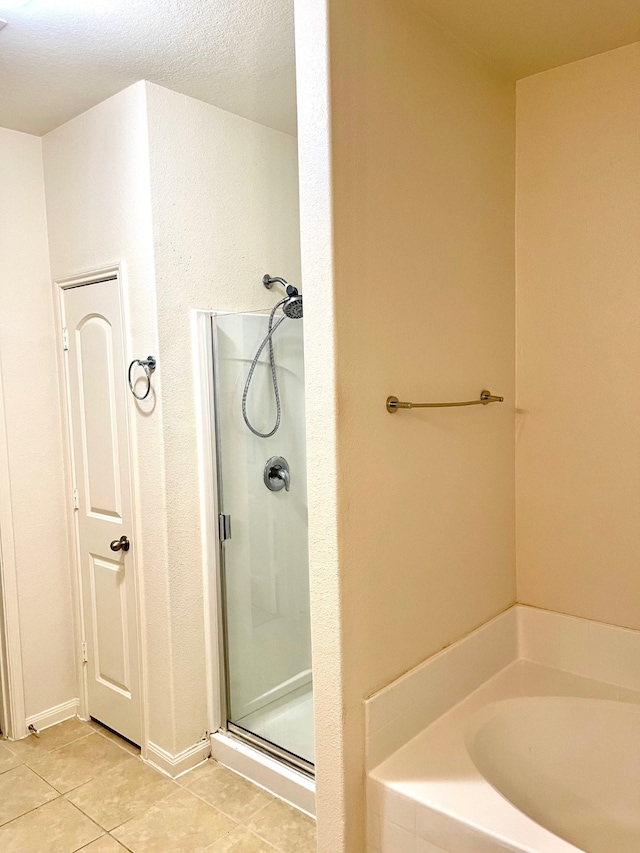 bathroom with tile flooring, shower with separate bathtub, and a textured ceiling