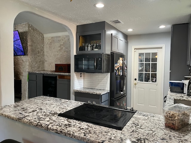 kitchen with cooktop, black fridge, gray cabinetry, beverage cooler, and backsplash