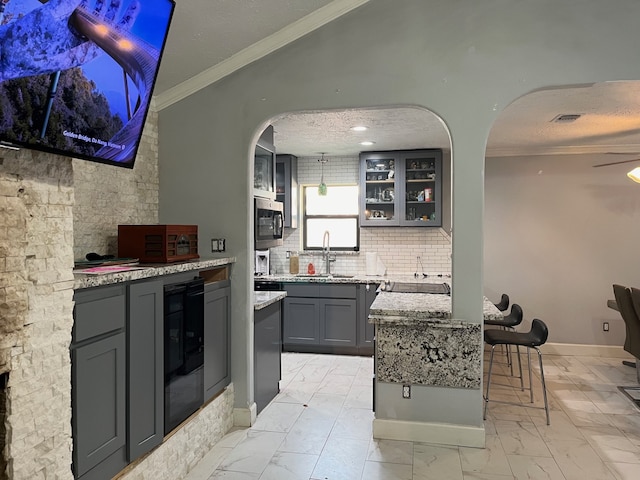 kitchen with a kitchen island, backsplash, gray cabinets, and light stone counters