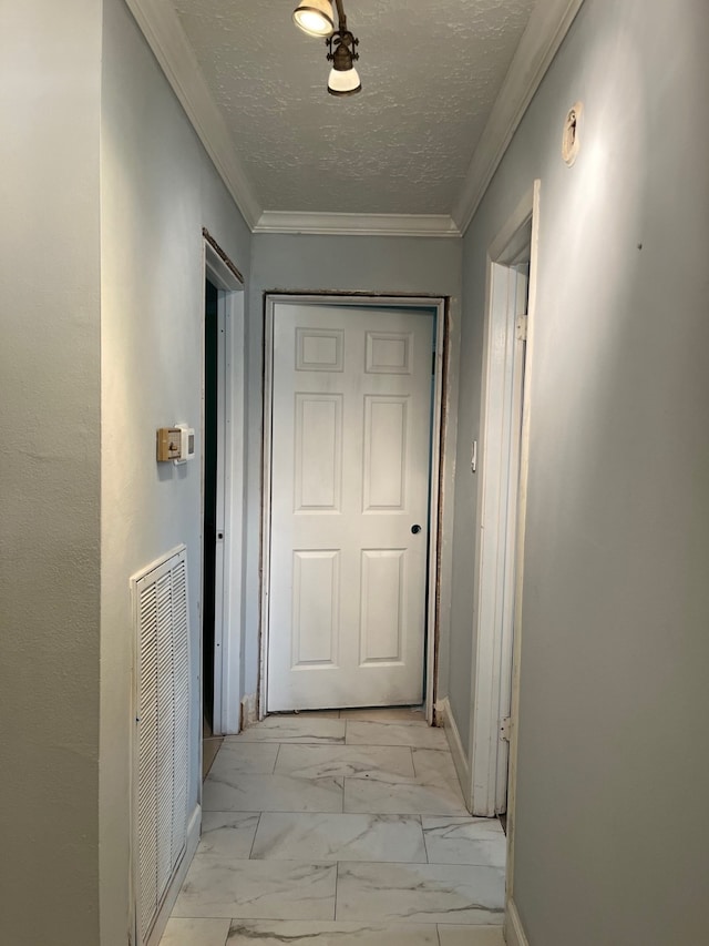 hallway featuring ornamental molding, light tile floors, and a textured ceiling