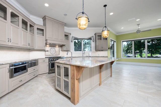 kitchen with high end range, a kitchen breakfast bar, hanging light fixtures, light stone countertops, and a center island with sink