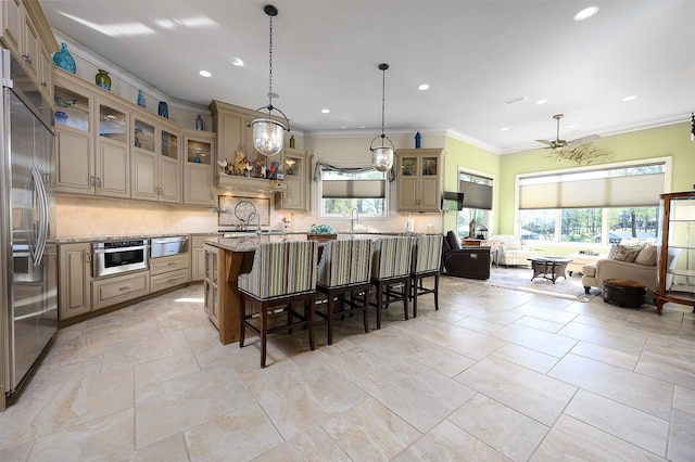 kitchen with a breakfast bar area, stainless steel appliances, light stone counters, an island with sink, and decorative backsplash