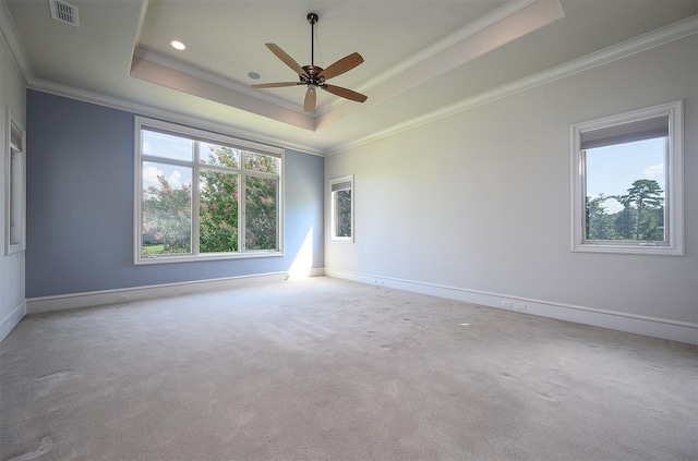 unfurnished room featuring a raised ceiling, crown molding, light carpet, and ceiling fan