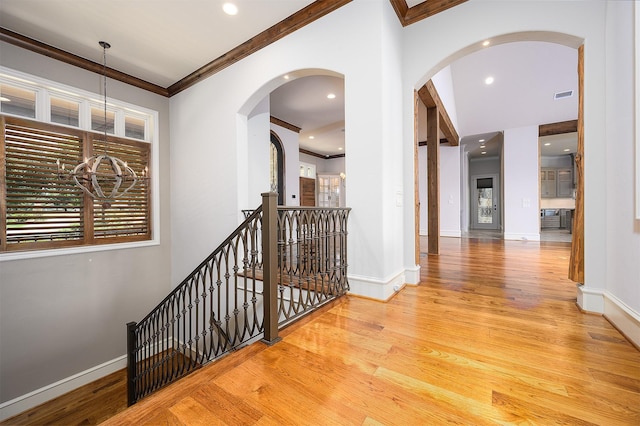 hall with ornamental molding and light hardwood / wood-style floors