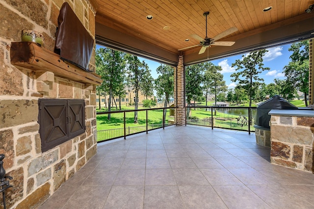 sunroom / solarium with ceiling fan, a water view, and wood ceiling