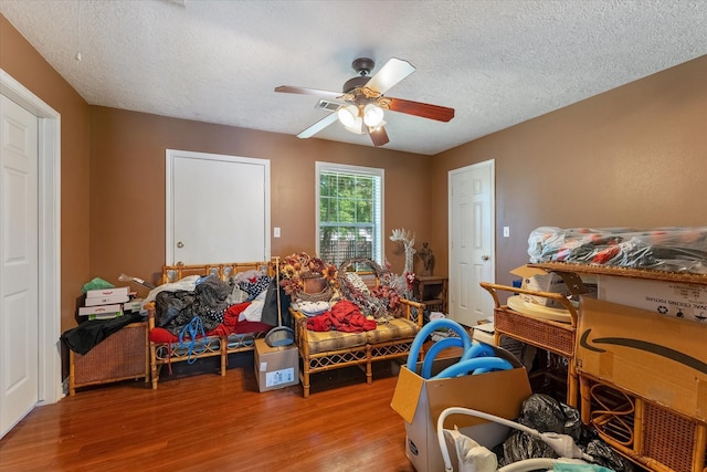 playroom featuring ceiling fan, light hardwood / wood-style floors, and a textured ceiling