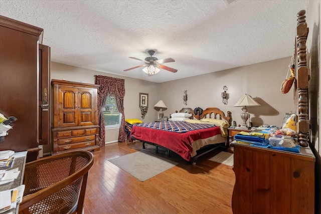 bedroom with hardwood / wood-style floors, a textured ceiling, and ceiling fan