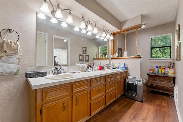 bathroom featuring heating unit, vanity, hardwood / wood-style flooring, and a textured ceiling