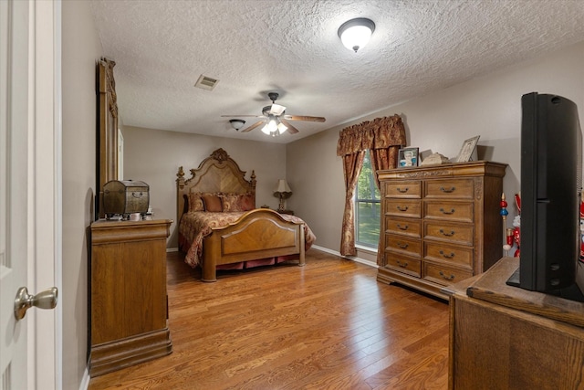 bedroom featuring hardwood / wood-style flooring, ceiling fan, and a textured ceiling