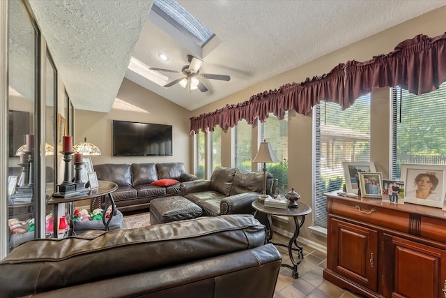 living room with a textured ceiling, lofted ceiling with skylight, ceiling fan, and light tile patterned flooring