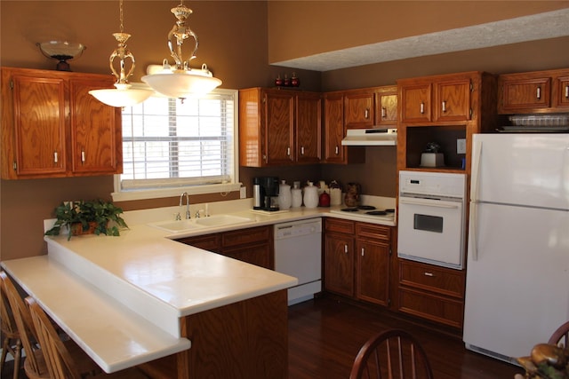 kitchen featuring sink, decorative light fixtures, dark hardwood / wood-style floors, kitchen peninsula, and white appliances