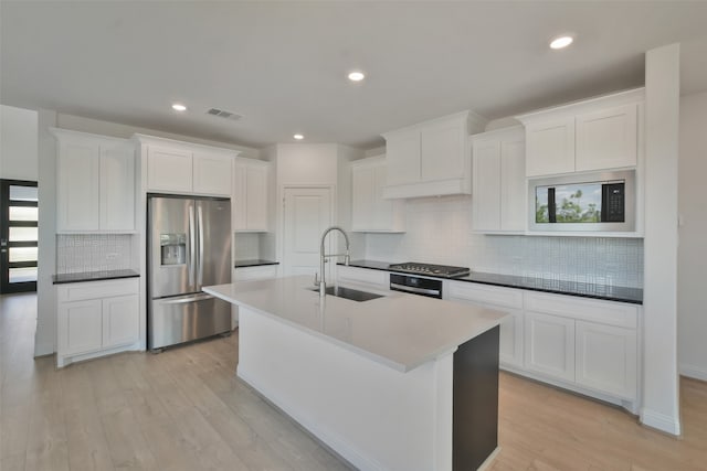 kitchen featuring sink, white cabinetry, light hardwood / wood-style flooring, decorative backsplash, and appliances with stainless steel finishes