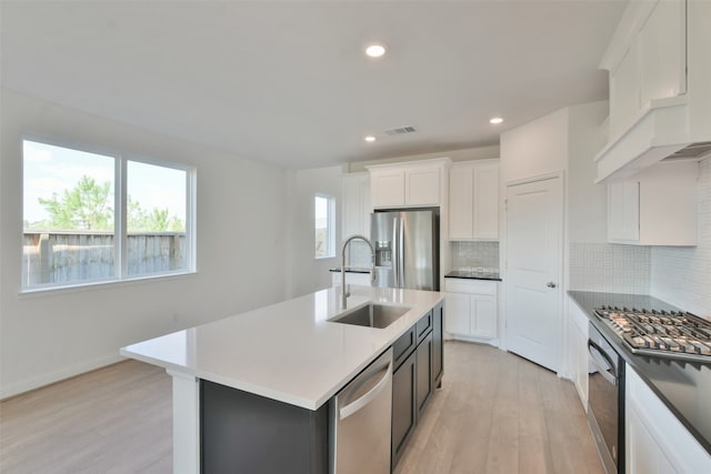 kitchen featuring light wood-type flooring, sink, an island with sink, white cabinetry, and stainless steel appliances