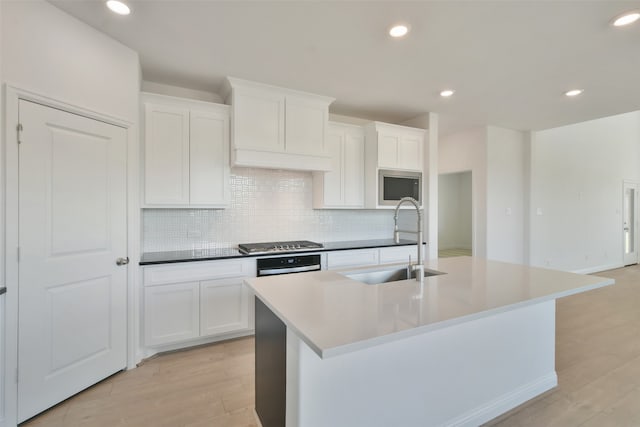 kitchen featuring white cabinetry, sink, stainless steel appliances, and an island with sink