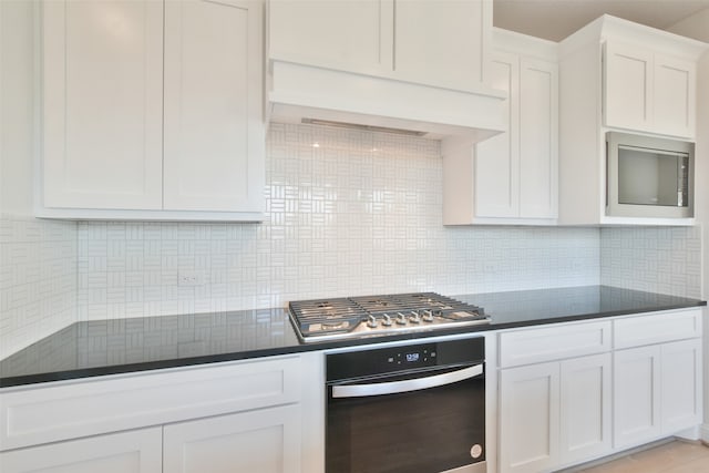 kitchen featuring ventilation hood, white cabinets, stainless steel appliances, and tasteful backsplash