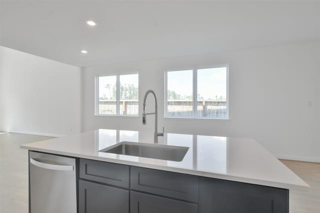 kitchen with gray cabinets, light hardwood / wood-style floors, sink, an island with sink, and stainless steel dishwasher