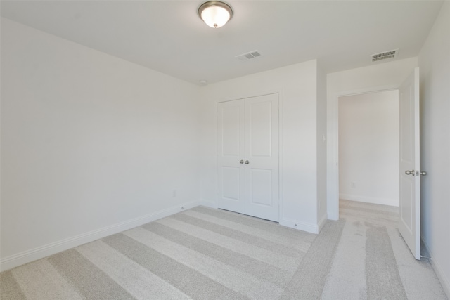 unfurnished bedroom featuring a closet and light colored carpet