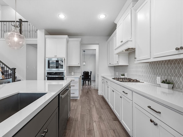 kitchen featuring backsplash, decorative light fixtures, and white cabinetry