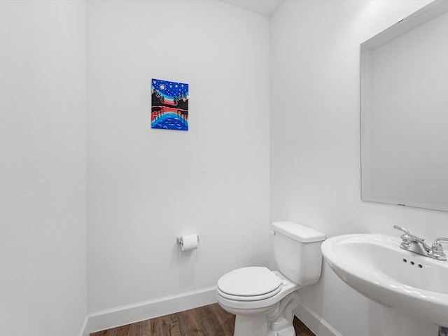 bathroom featuring toilet, wood-type flooring, and sink