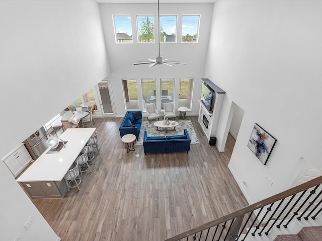 living room featuring ceiling fan, a high ceiling, and hardwood / wood-style flooring