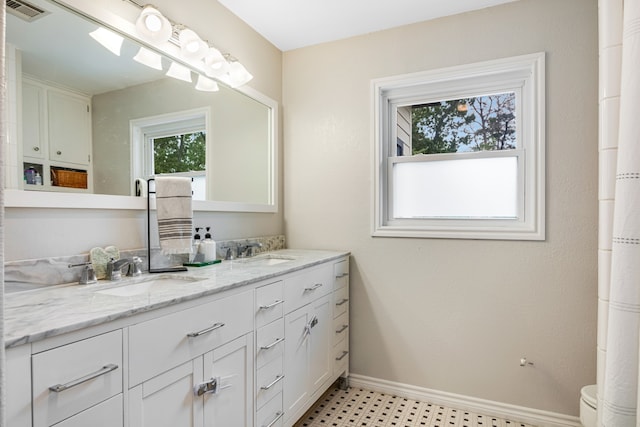 bathroom featuring double sink, tile flooring, toilet, and vanity with extensive cabinet space