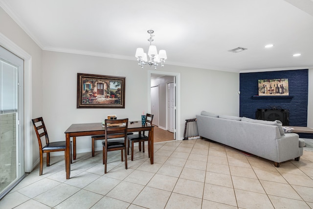 dining room featuring crown molding, light tile flooring, a fireplace, and a chandelier