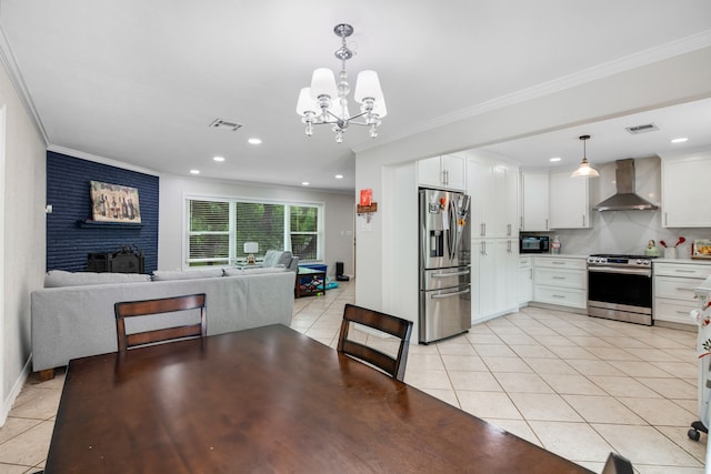 kitchen featuring white cabinets, hanging light fixtures, stainless steel appliances, and wall chimney exhaust hood