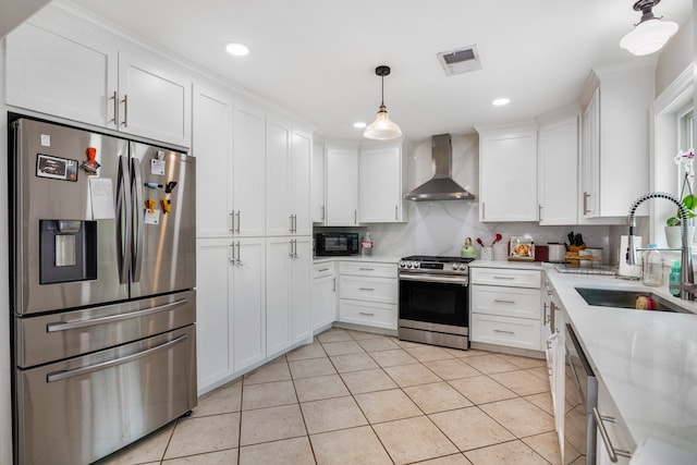 kitchen with appliances with stainless steel finishes, wall chimney range hood, sink, light stone countertops, and white cabinets