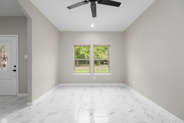 tiled empty room featuring ceiling fan