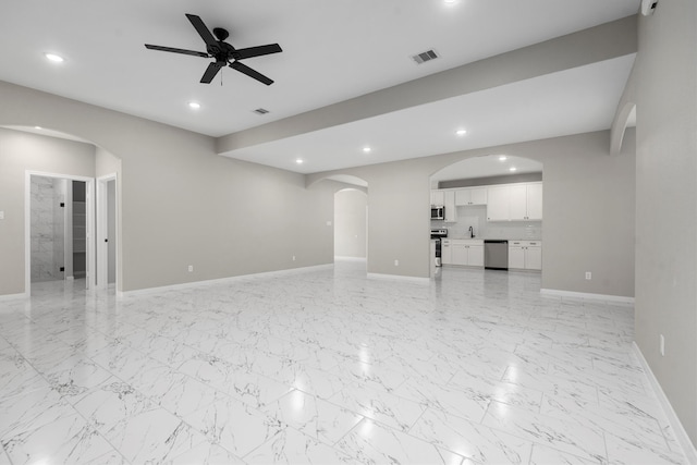 unfurnished living room with ceiling fan, light tile floors, and sink