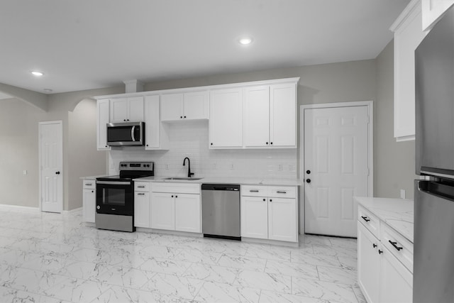 kitchen featuring stainless steel appliances, light tile flooring, white cabinetry, and sink