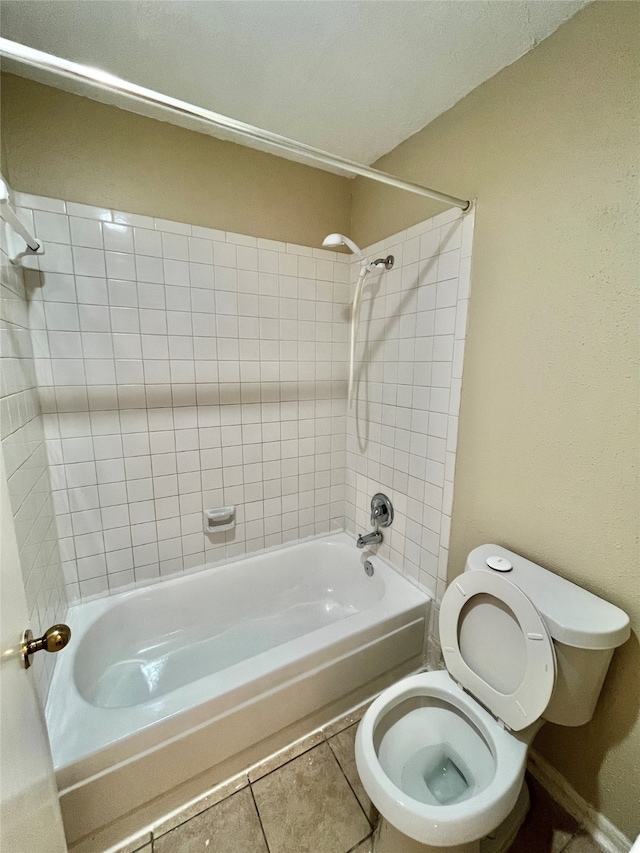 bathroom with tile patterned floors, toilet, and tiled shower / bath combo