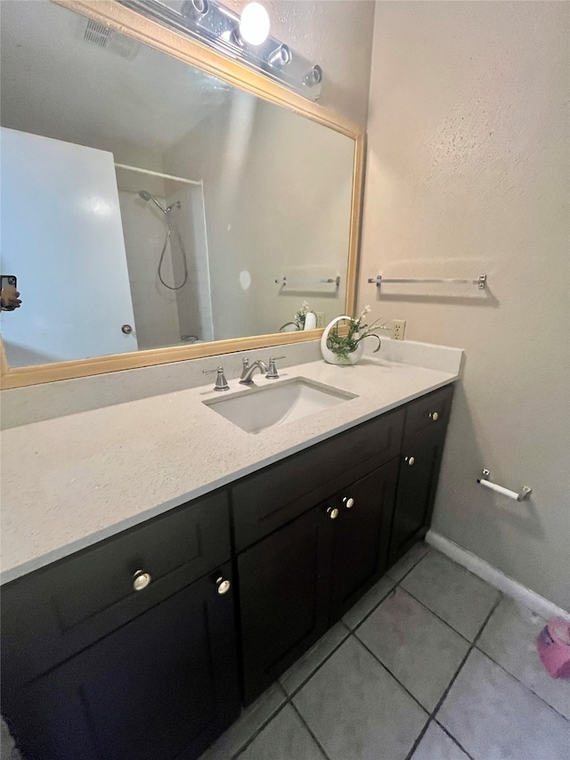 bathroom featuring vanity, tile patterned flooring, and a shower