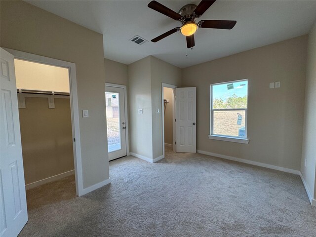 unfurnished bedroom featuring ceiling fan, light colored carpet, a spacious closet, and a closet