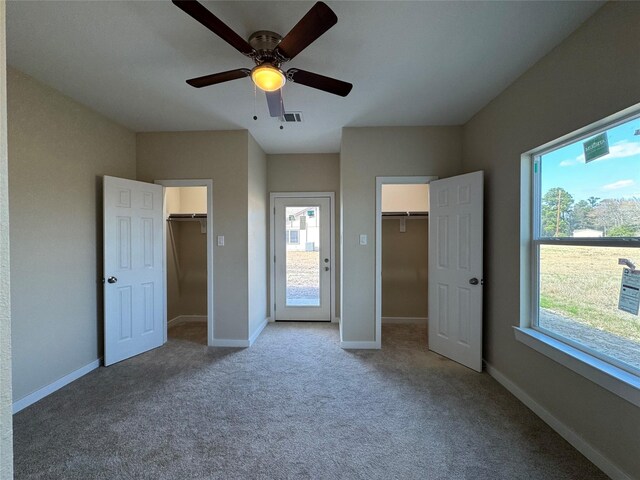 unfurnished bedroom with ceiling fan, a walk in closet, and carpet flooring