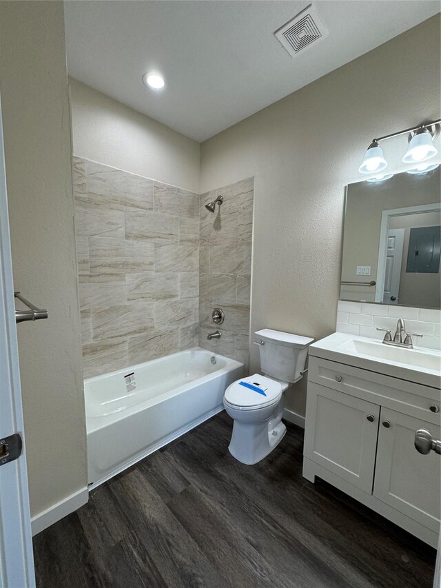 full bathroom with tasteful backsplash, hardwood / wood-style flooring, vanity, tiled shower / bath combo, and toilet