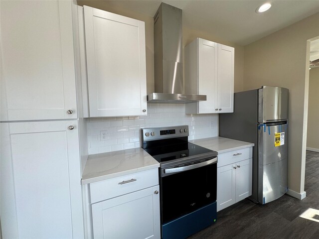 kitchen with wall chimney exhaust hood, white cabinetry, light stone counters, stainless steel appliances, and backsplash